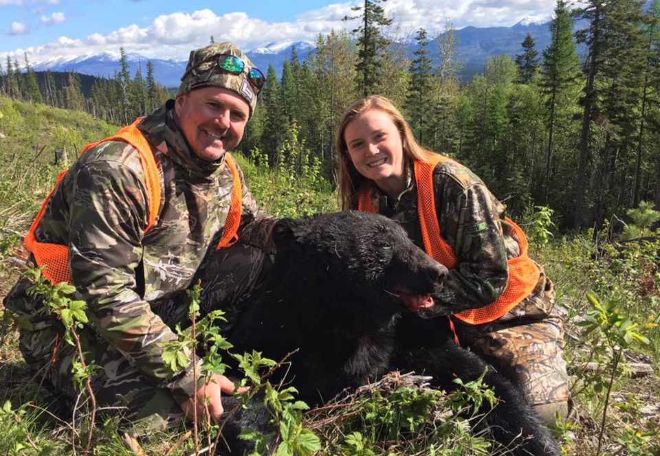 Beau Beaullieu and his daughter pose with a bear after a hunt in the wilderness.