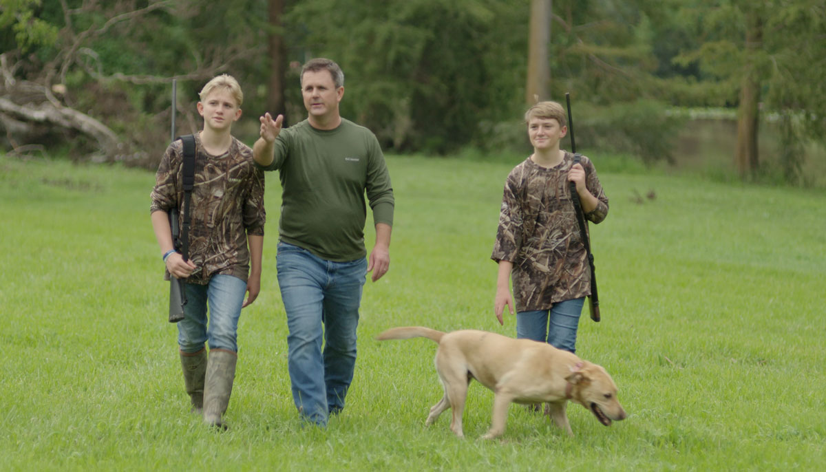 Beau Beaullieu and his sons walking through a field on a hunting trip